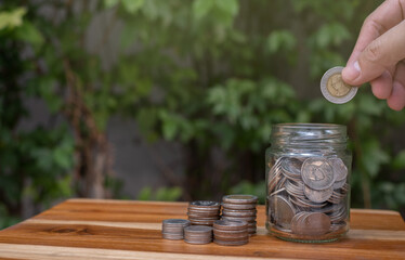 coin saving hand on wooden table and natural background saving money for future retirement or investment