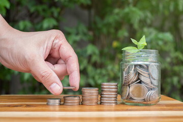 money saving hand in a jar, with natural lighting and coin in the jar growing in to little sprout and green natural light