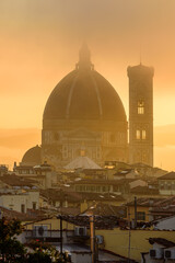 Obraz premium The Florence Cathedral in a golden misty sunrise early morning.