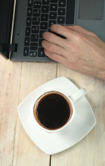 a cup of coffee on the table with a laptop