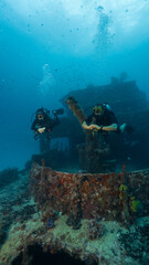 Fototapeta premium couple of divers posing in front of a sunken ship, technical diving