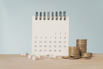 For payday loan concept. White calendar and blurred stack of coins , blurred white thumbtack on...