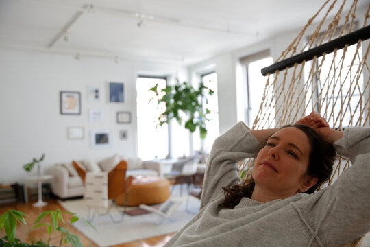 Thoughtful woman relaxing on hammock at home