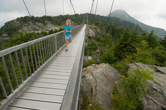 A woman running across suspension bridge at Grandfather Mountain, Linville, North Carolina.