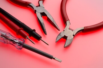 Electrical tools, wire cutters, multimeter indicator screwdriver. Multicolored background. Close-up