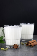A glass of Indian cold drink based on yogurt dahi - Lassi with spices and mint on a black background. The concept of fermented foods. Indian food. Copy space.