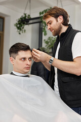 Barber shaving caucasian man in barber shop.