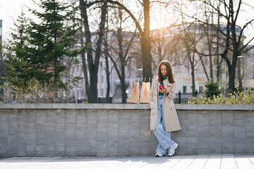 Fototapeta premium Woman with a shopping bags chatting by phone in a city park after shopping time 