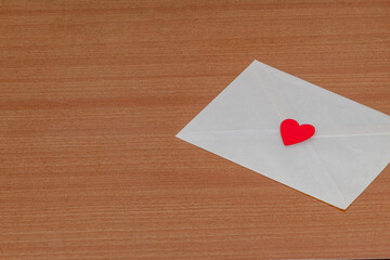 Carta de amor por San Valentín en el interior de un sobre blanco cerrado y sellado con un corazón rojo sobre un fondo de madera por un enamorado.