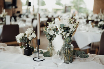 Weiße Blumen und Kerzen auf gedecktem Hochzeitstisch