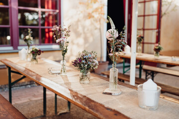 Fototapeta na wymiar Bunte Blumen und Kerzen auf gedecktem Hochzeitstisch