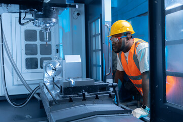 Engineer african man worker checks and inspects metal part after processed on CNC automated machine