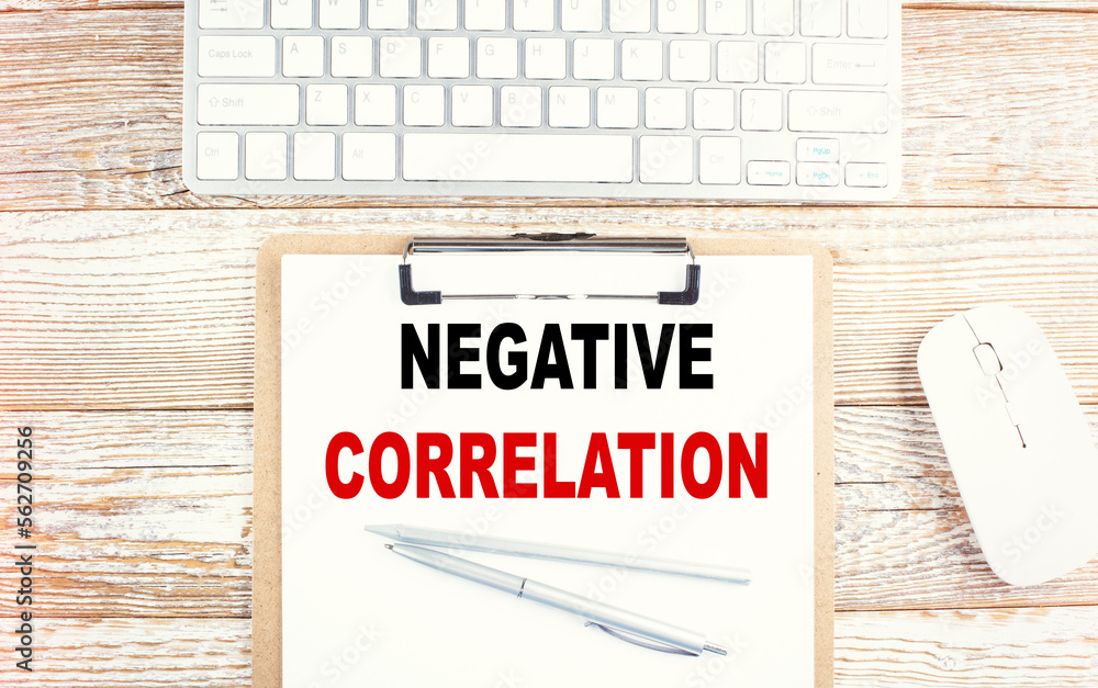 Poster negative correlation text on a clipboard with keyboard on wooden background
