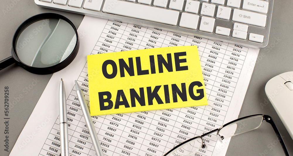 Poster online banking text written on a sticky on chart with keyboard and magnifier