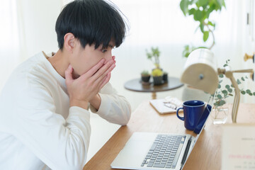 パソコンを見て驚く若い男性