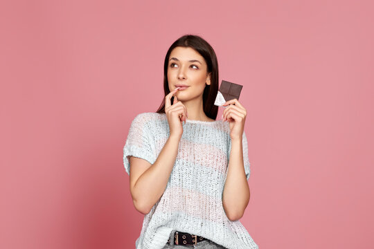 young woman in sweater holding chocolate bar