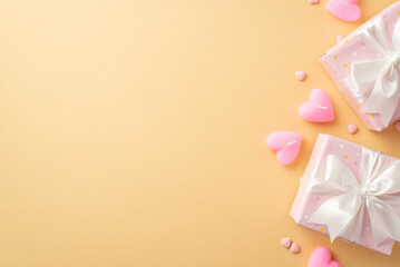 Valentine's Day concept. Top view photo of gift boxes with white ribbon bows heart shaped candles and sprinkles on isolated pastel beige background with copyspace