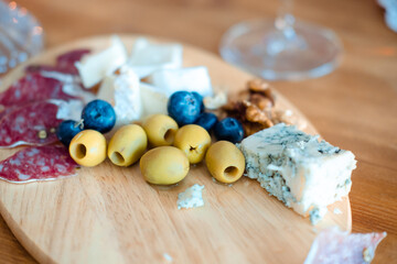 olives, cheese, nuts on a wooden tray on the table. Snacks for wine