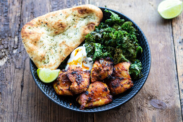 Spicy chicken thighs with crispy kale and naan bread