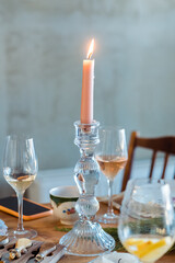 pink candle in a candelabra on a table close-up with glasses of wine and champagne