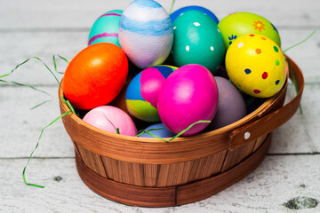 Basket with painted colorful easter eggs on wooden table