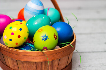 Basket with painted colorful easter eggs on wooden table