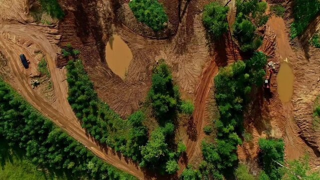 Aerial shot of heavy machinery in nature digging around a forest 