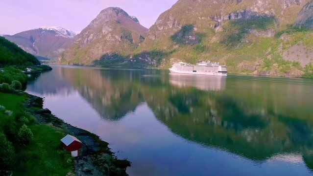 Stunning aerial ogf a still lake reflecting the mountains in the water with a ferry sailing by