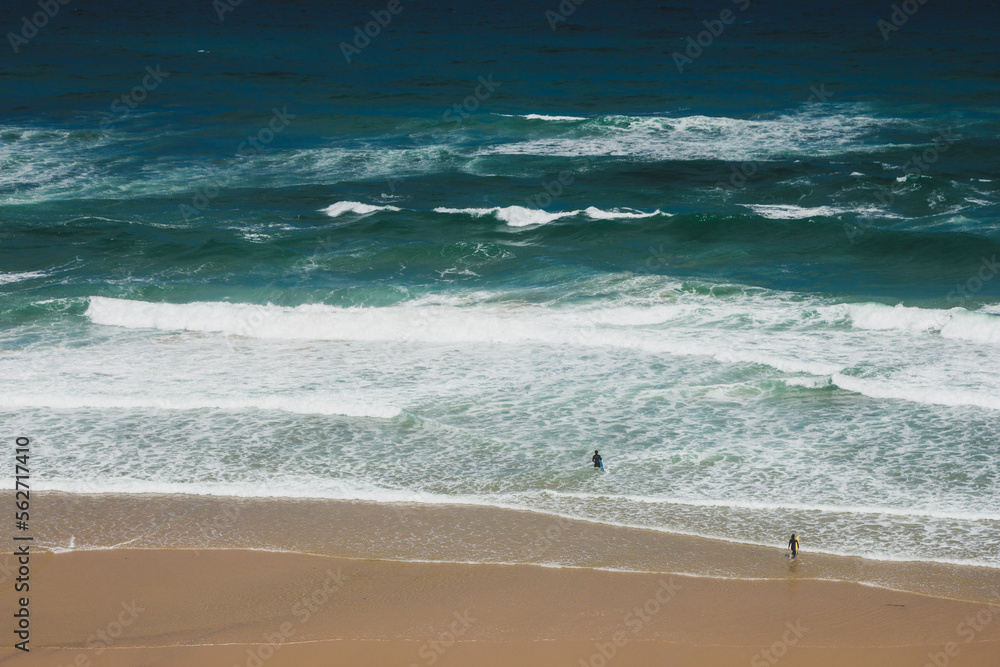 Wall mural view of beach with large waves near atlantic coast. surfers on the ocean coast with surfboard. praia