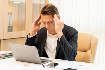 Male executives sitting at work, financial, using hands to hold the temple on both sides, feel...