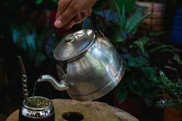 mano cebando mate, pava de acero y mate tradicional argentino con yerba mate, disfrutando de un...