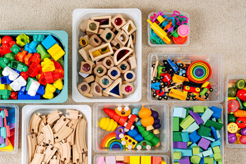 Toy Storage boxs in the children's room. Plastic containers with colorful wooden toys. Organizing and Storage Ideas in nursery. Clean up toys and reduce the clutter. Top view