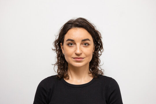 A beautiful woman on a white background looks directly into the camera 