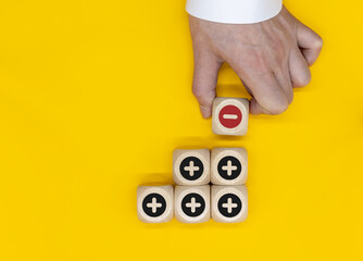 Plus and minus icons on wooden cubes. Separate the negative from positive, removing the weaknesses...