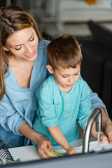 Obraz premium Son is helping mother in the Kitchen, Washing Dishes