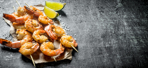 Shrimps fried on skewers with slices of lime.