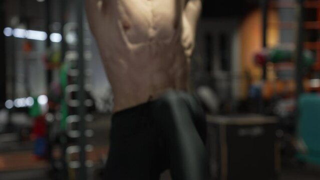 Athlete with fit torso crop view doing hanging leg-lift in fitness gym. Fitness bar exercises