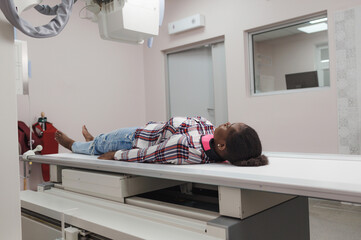an African-American girl is a patient lying on the surface of an apprarat for X-ray examination