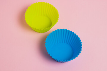 Yellow and blue silicone cupcake molds on a pink paper background