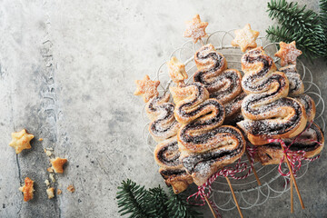 Christmas tree shape puff pastry cakes with chocolate filling, sugar powder and lollipops on old white wooden background. Christmas, New Year Appetizer. Festive idea for Christmas or New Year dinner.