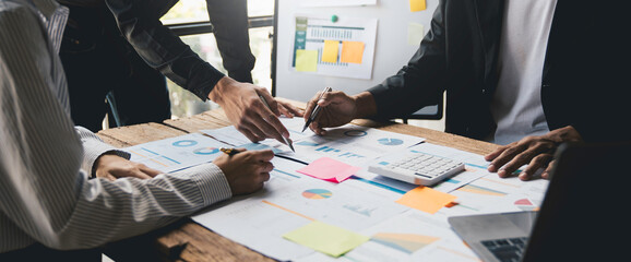 A group of Asian business people is meeting for a project to establish and plan. Discussion of graphs and chart data analysis business finance graph and accounting concept.