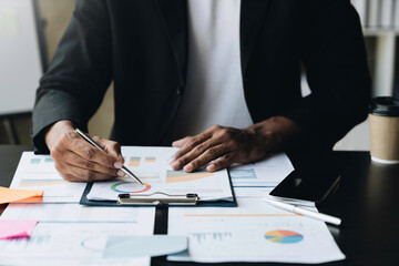 Young Asian businessman discussing graphs with hands and analyzing data. clarify pie chart details and Graph showing the average in business finance and accounting concept.