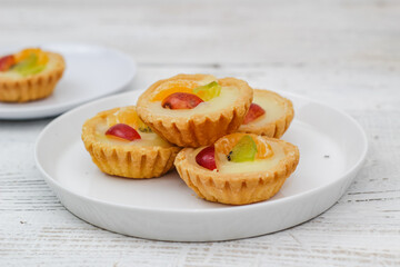 Small fruit pia cake on a textured white background. Kue Pia Buah.
