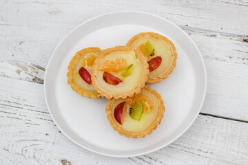 Small fruit pia cake on a textured white background. Kue Pia Buah.