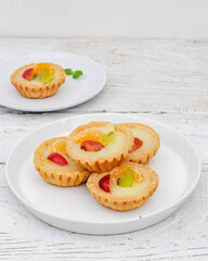 Small fruit pia cake on a textured white background. Kue Pia Buah.