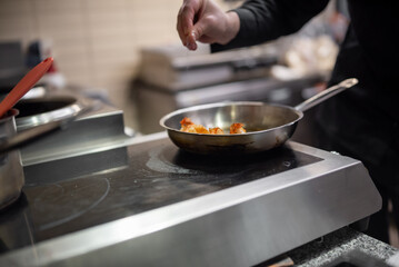 man chef cooking fried shrimp in frying pan on kitchen