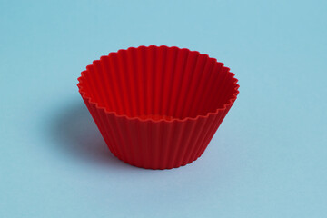 Red silicone mold for a cupcake on a light blue paper background