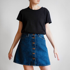 Woman wearing black t-shirt and denim mini skirt isolated on white background.
