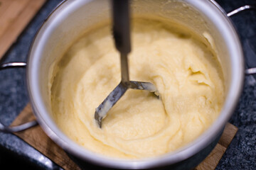 Mashing potatoes with a hand in a pot - sometimes called smashed potatoes - Shallow focus
