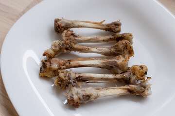 Multiple chicken bones on a white plate